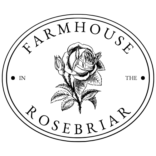 This is a picture of a black and white website logo for the blog named "Farmhouse In The Rosebriar". The logo consists of a horizontal oval shaped and outline of the overall design, Inside of the oval design is a digital graphic of a Victorian-era-style illustrated rose, with the words, "Farmhouse In The Rose briar", which is the name of the blog associated with the logo and it's website and domain name. The logo consists of all upper-case letters and the design is a classic and timeless black and white design.